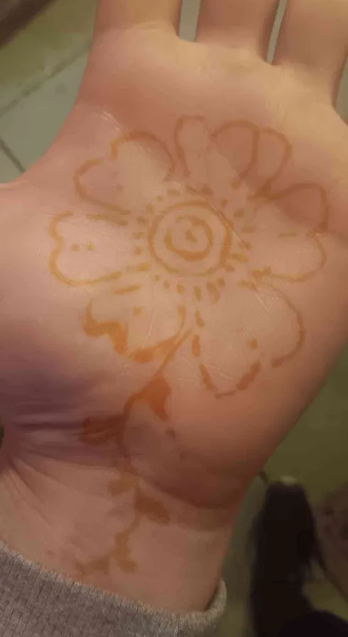 my palm with a five petal flower henna design on it