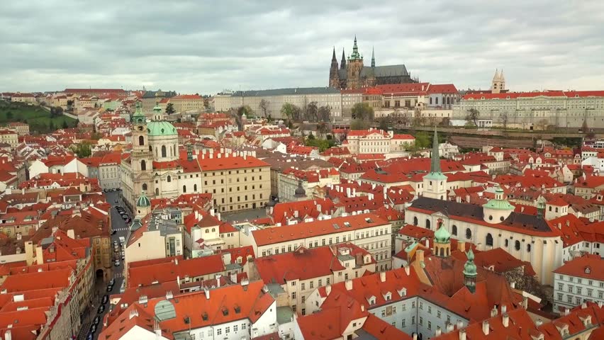 An image of Prague near prague castle, lots and lots of buildings with matching roofs and a massive gothic cathedral in the background.